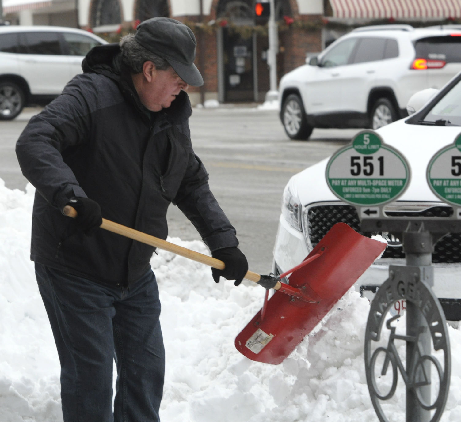 Gary Petzinger, co-owner of Constant Cravings LLC in downtown Lake Geneva, shovels snow in front of his business